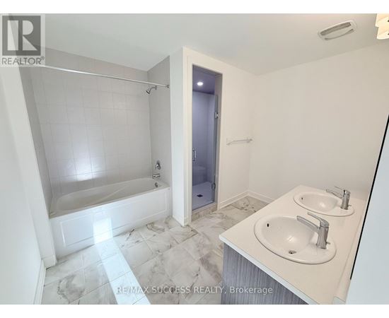 A white bathroom with a marble floor and a walk-in shower.