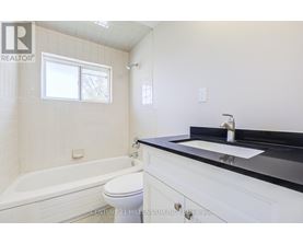 A bathroom with a white tub, sink, and toilet.