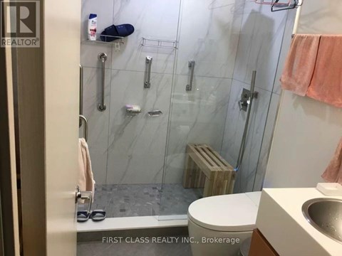 A bathroom with a marble shower and toilet.