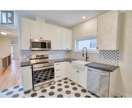 A kitchen with white cabinets and a black and white checkered floor.