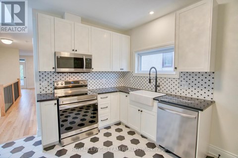 A kitchen with white cabinets and a black and white checkered floor.