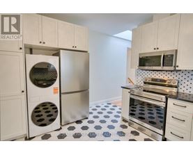 A kitchen with white cabinets and a black and white checkered floor.