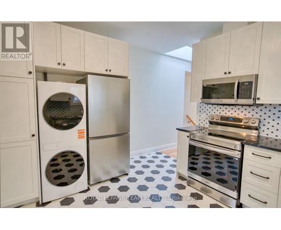 A kitchen with white cabinets and a black and white checkered floor.