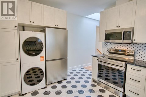 A kitchen with white cabinets and a black and white checkered floor.