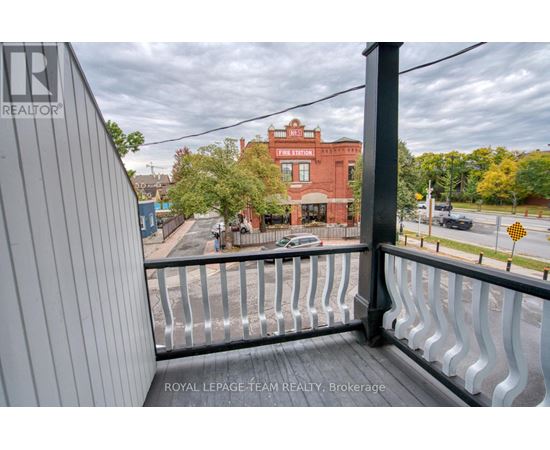 A balcony with a metal railing overlooks a street with cars and buildings.