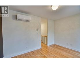 A white wall with a light switch and a wall-mounted air conditioner.