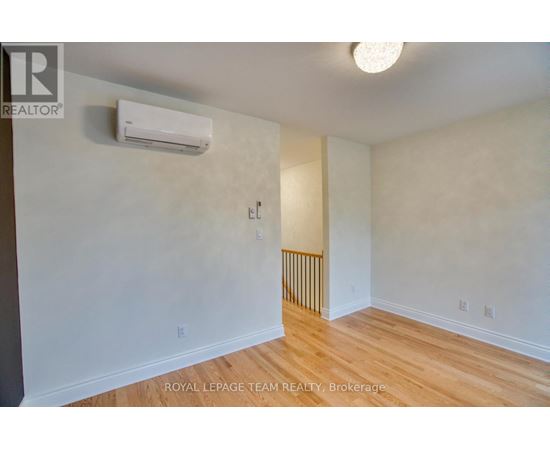A white wall with a light switch and a wall-mounted air conditioner.
