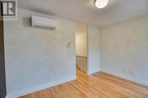 A white wall with a light switch and a wall-mounted air conditioner.