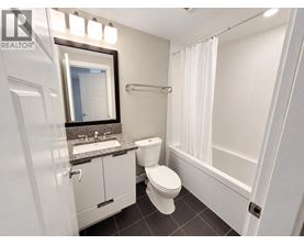 A white toilet sits in a bathroom with a sink and mirror.