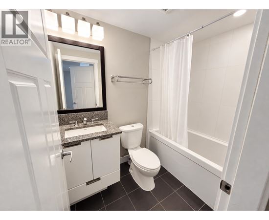 A white toilet sits in a bathroom with a sink and mirror.