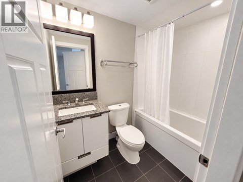 A white toilet sits in a bathroom with a sink and mirror.
