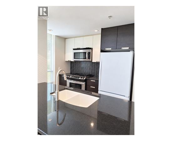 A modern kitchen with a white fridge and black cabinets.
