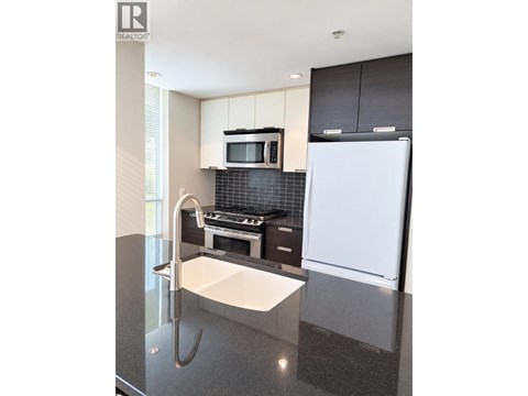 A modern kitchen with a white fridge and black cabinets.