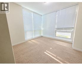 A room with a carpeted floor and a window with blinds.