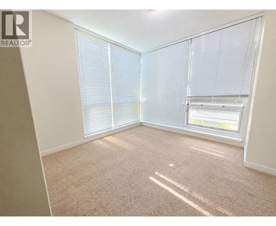 A room with a carpeted floor and a window with blinds.