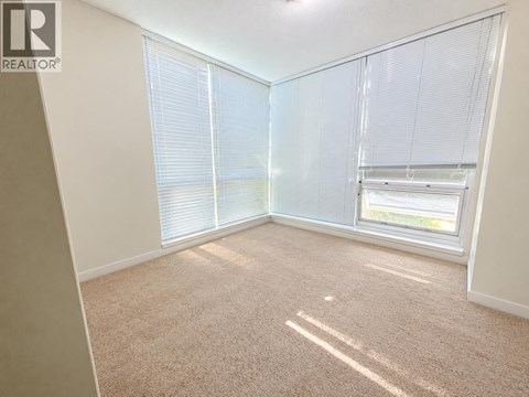 A room with a carpeted floor and a window with blinds.