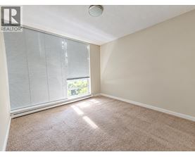 A room with a carpeted floor and a window with blinds.