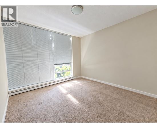A room with a carpeted floor and a window with blinds.