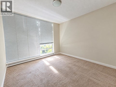 A room with a carpeted floor and a window with blinds.