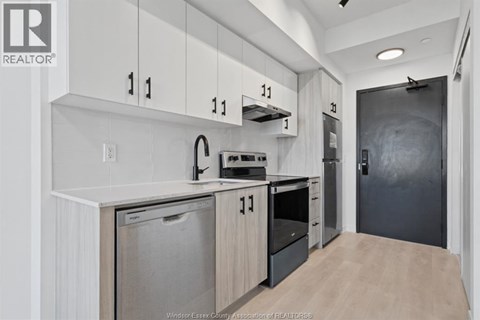 A kitchen with white cabinets and a black refrigerator.