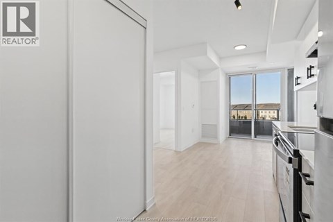 A realtor logo is on the wall of a spacious, empty room.