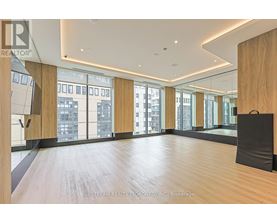 A spacious room with wooden floors and large windows overlooking a cityscape.