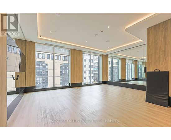 A spacious room with wooden floors and large windows overlooking a cityscape.