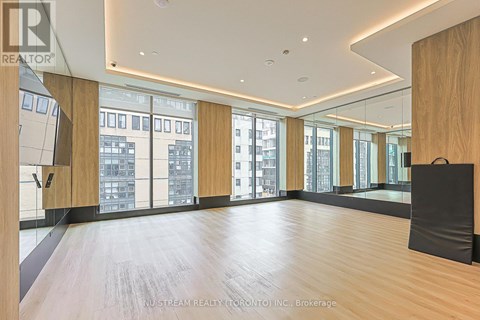 A spacious room with wooden floors and large windows overlooking a cityscape.