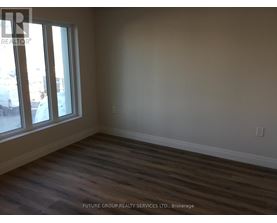 A room with wooden flooring and a window overlooking a parking lot.