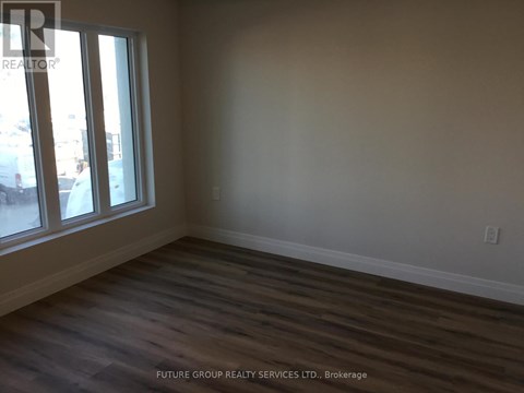 A room with wooden flooring and a window overlooking a parking lot.