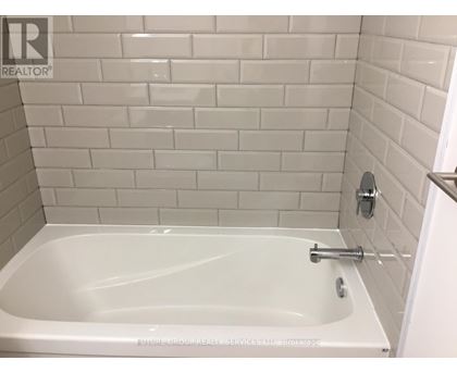 A white bathtub in a bathroom with white tiles.