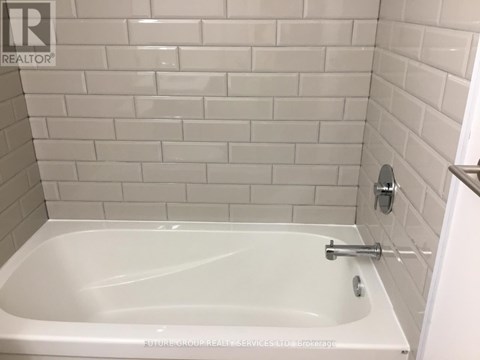 A white bathtub in a bathroom with white tiles.