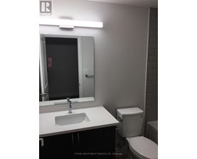 A bathroom with a sink, toilet and mirror.