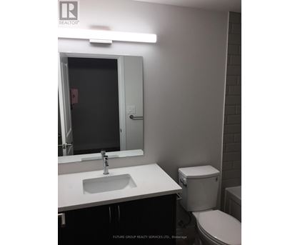 A bathroom with a sink, toilet and mirror.