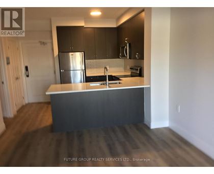 A kitchen with a stainless steel refrigerator and dark wood flooring.