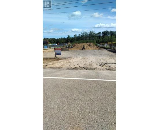 A construction site with a sign in the foreground and a road in the background.