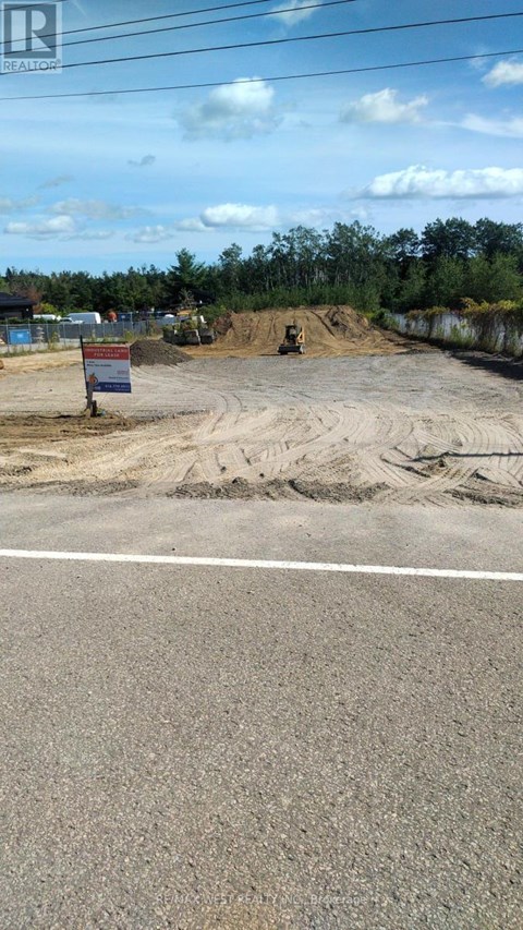 A construction site with a sign in the foreground and a road in the background.