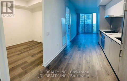 A spacious kitchen and living room with wood flooring and white walls.