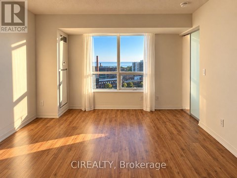 A room with wooden floors and a large window overlooking a cityscape.