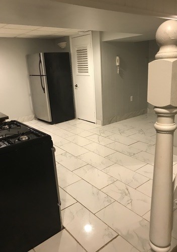 A kitchen with a black stove top oven and a black fridge.
