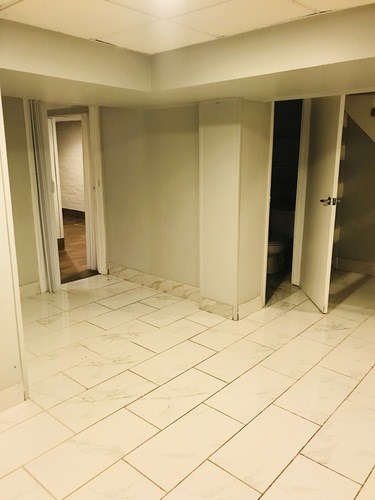 A room with white tiled floors and white walls with three doors.