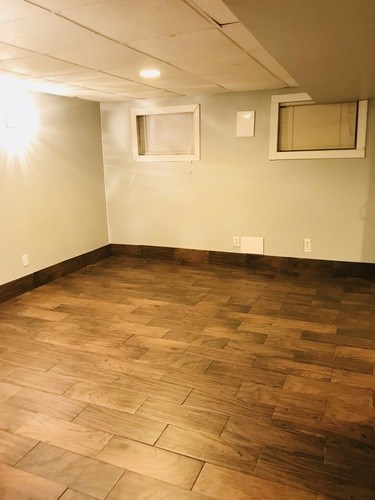 A room with wooden flooring and two windows.