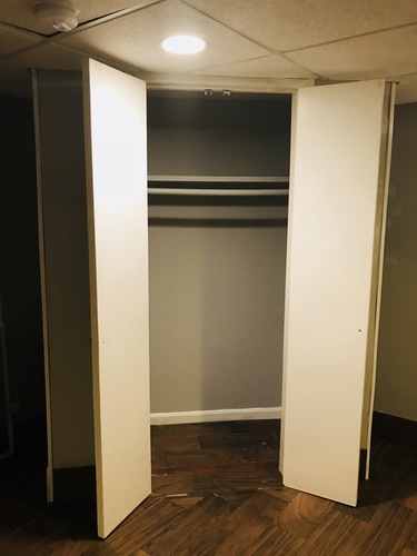 A white door is open in a room with wood flooring.