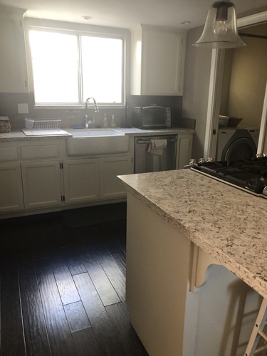 A kitchen with a granite counter top and wooden floors.
