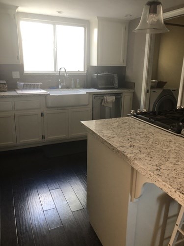 A kitchen with a granite counter top and wooden floors.