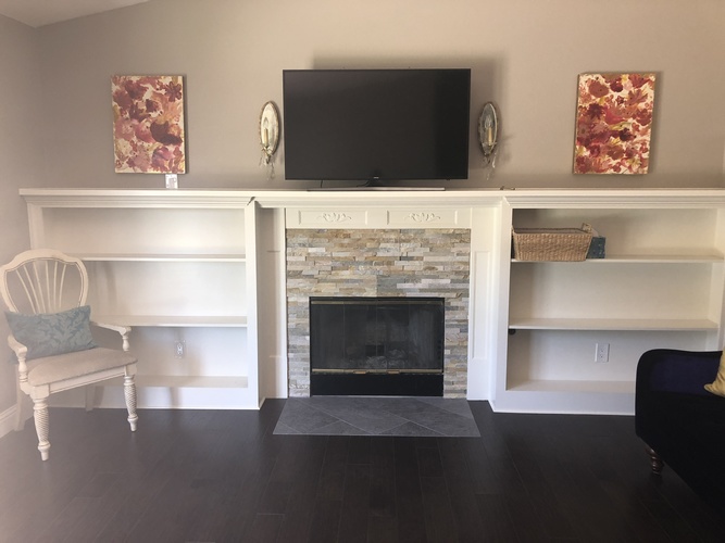 A living room with a fireplace and a television above it.
