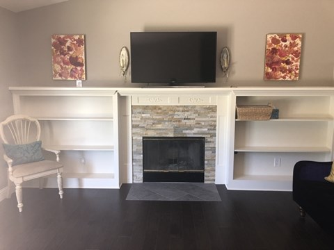 A living room with a fireplace and a television above it.