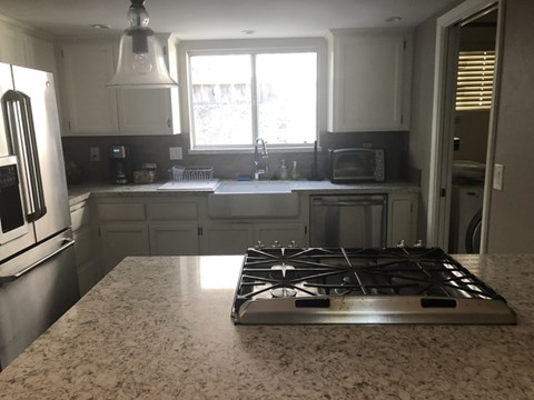A modern kitchen with a granite countertop and a stove top.