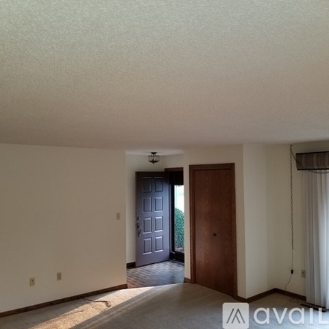 A room with a wooden door and a window with curtains.