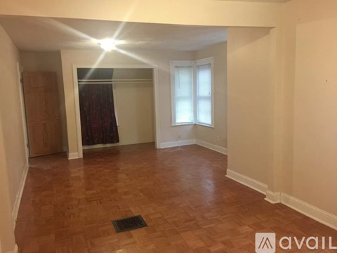 A room with wooden flooring and a window with curtains.
